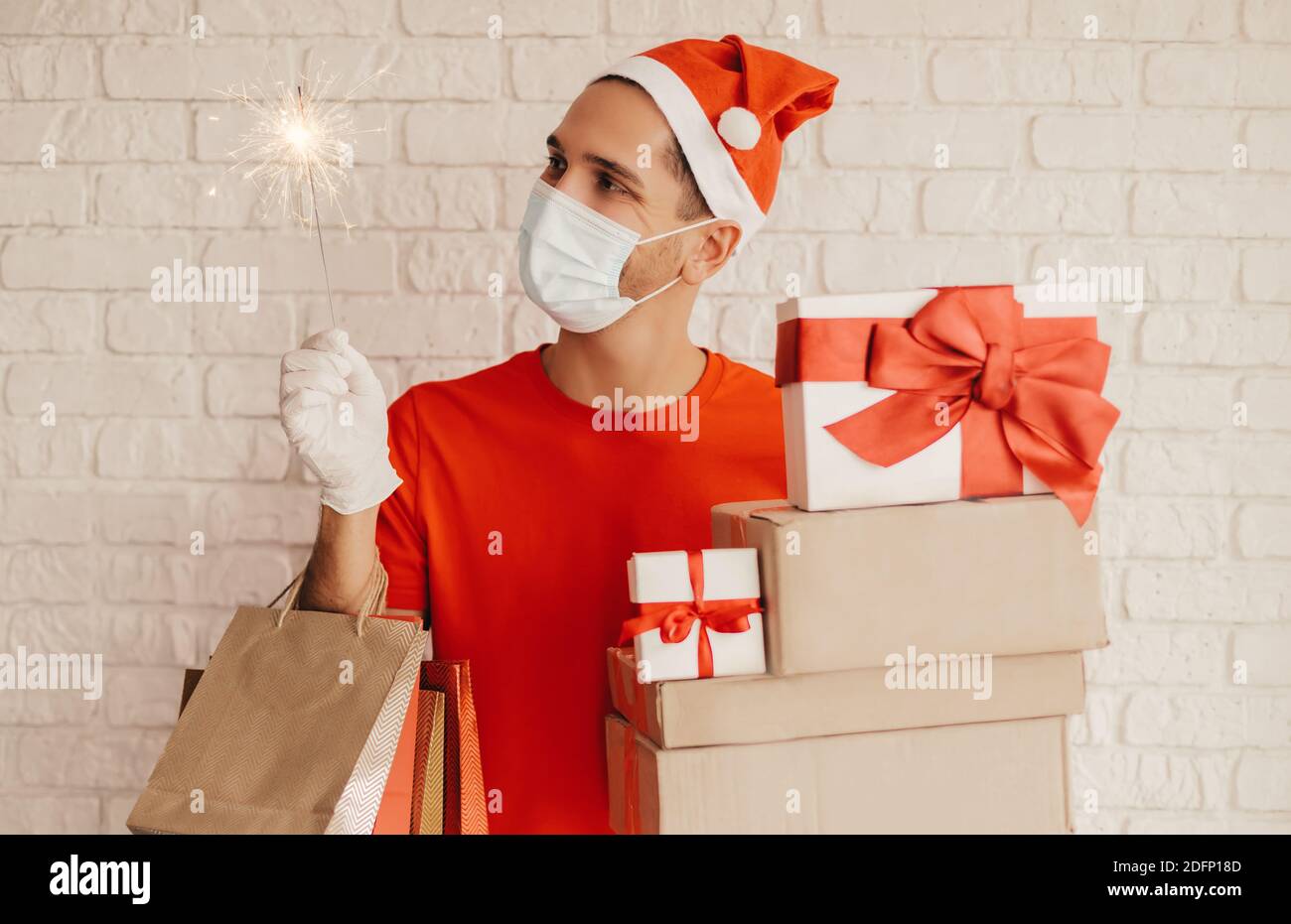 https://c8.alamy.com/comp/2DFP18D/young-man-courier-in-medical-face-mask-protective-gloves-santa-hat-deliver-christmas-new-year-presents-happy-delivery-man-hold-sparkler-light-sho-2DFP18D.jpg