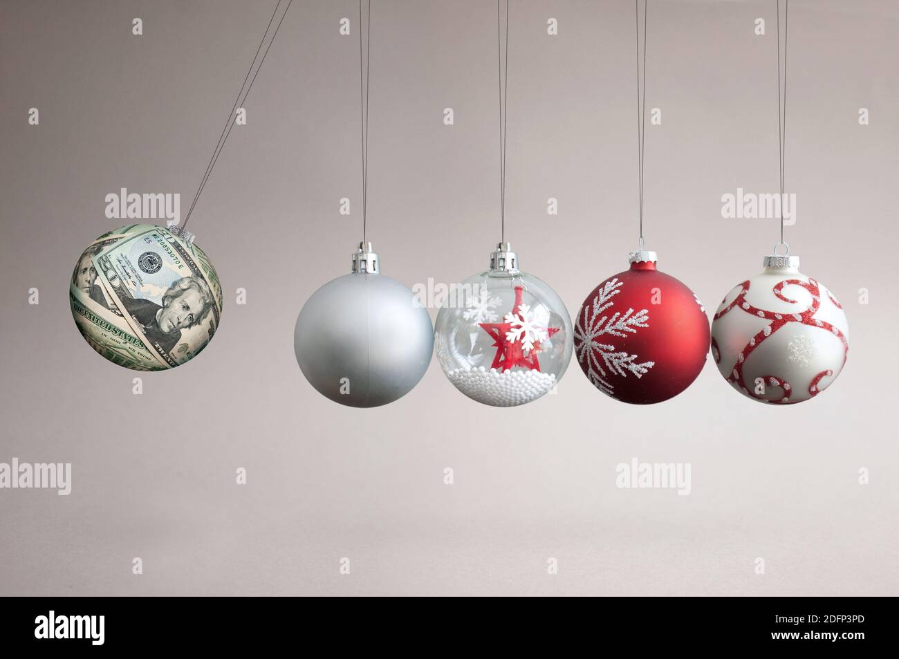 Dollar bauble colliding into christmas ornaments, seasonal shopping budget and balancing finances concept Stock Photo