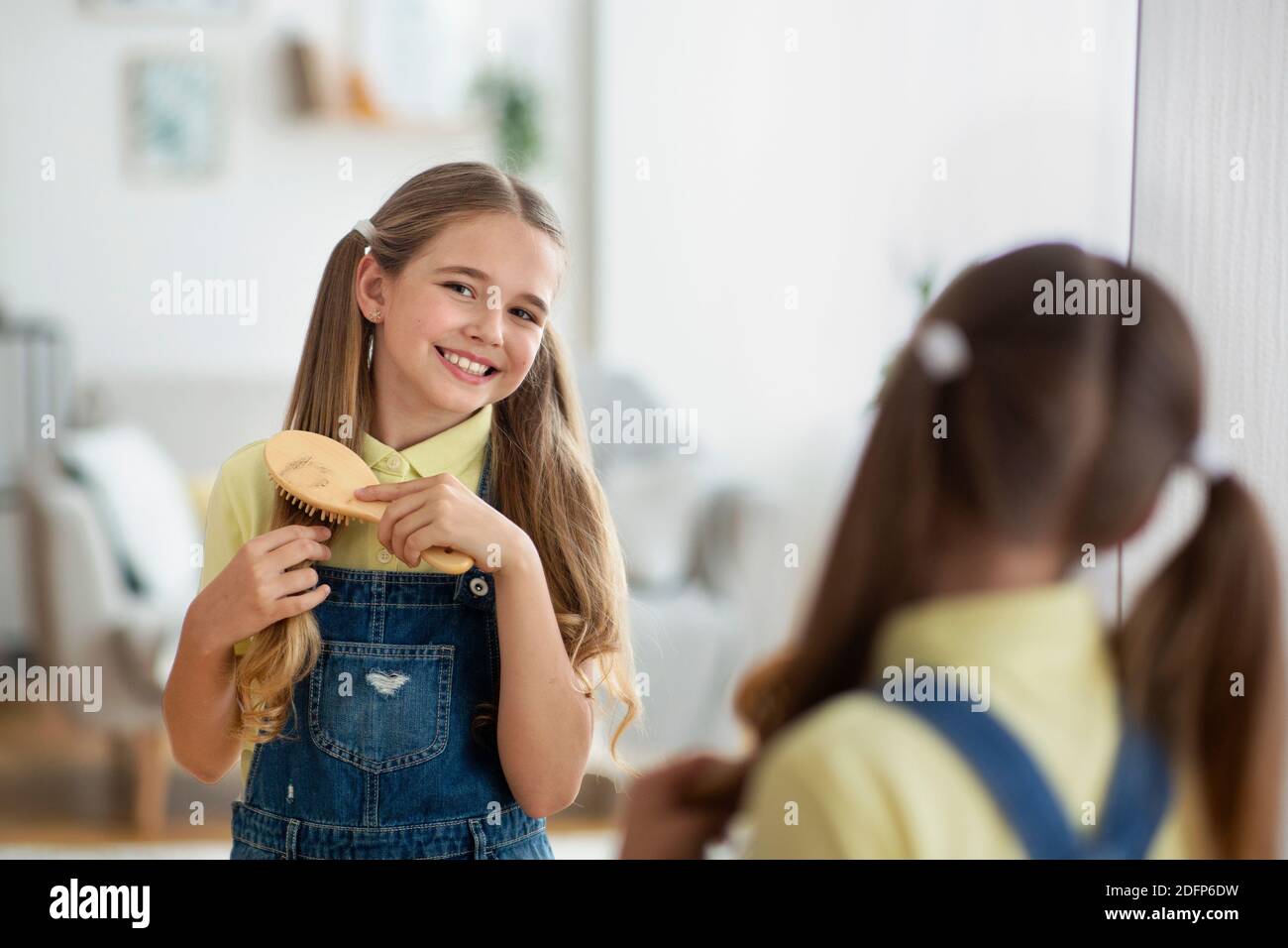 Girl in front of a mirror brushing her hair Stock Photo