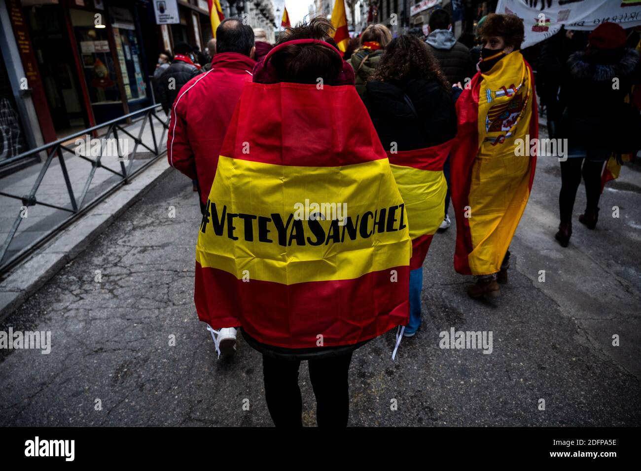 Madrid, Spain. 06th Dec, 2020. A protester wearing a Spanish flag with the words 'Sanchez go away now' during a demonstration marching to the Congress of Deputies to protest against the Government and demanding the resignation of President Pedro Sanchez coinciding with the central act on the day of the celebration of the Spanish Constitution that is celebrated within the Congress of Deputies. Credit: Marcos del Mazo/Alamy Live News Stock Photo