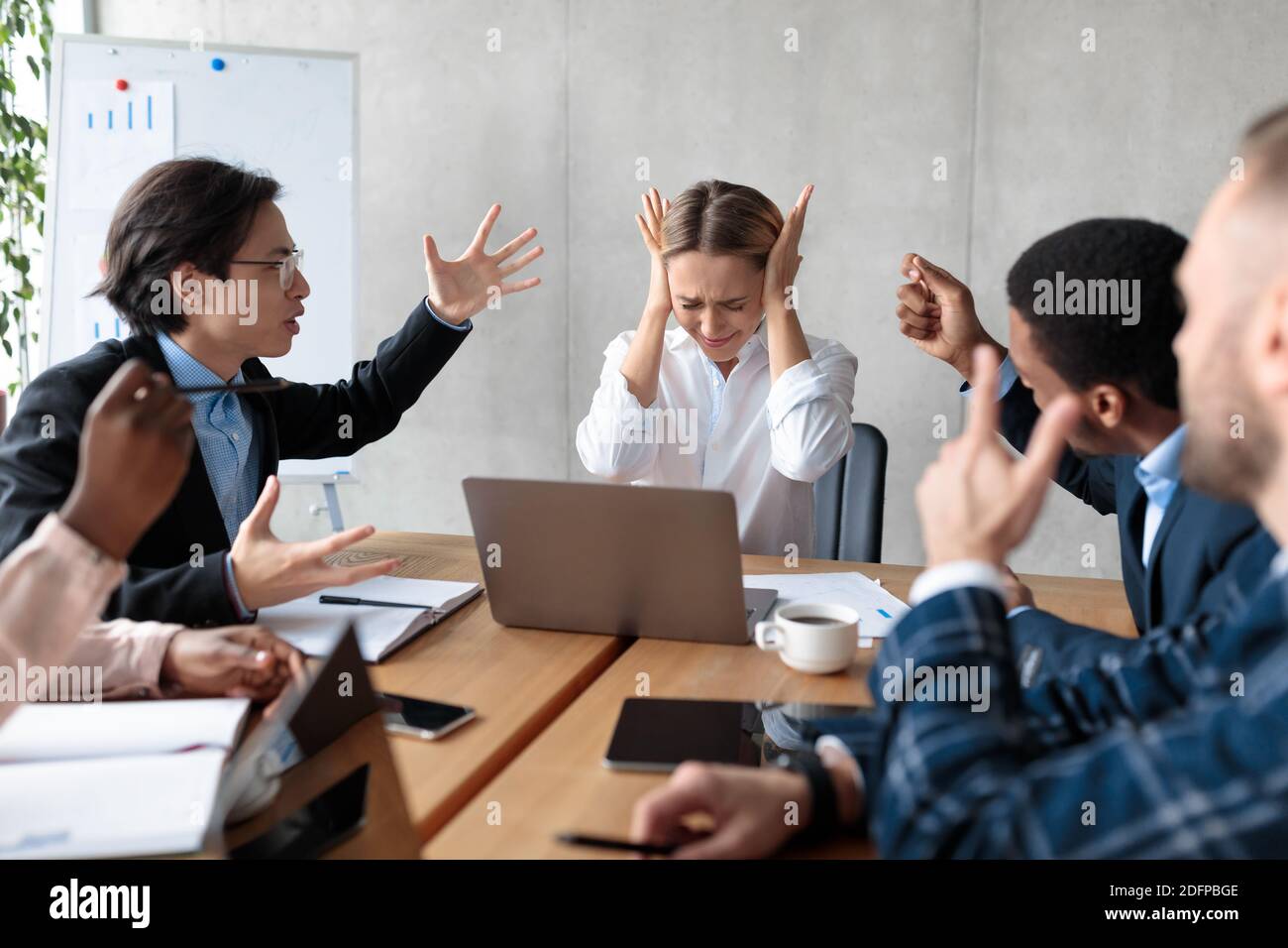 Business People Having Conflict Shouting At Unhappy Businesswoman At Workplace Stock Photo