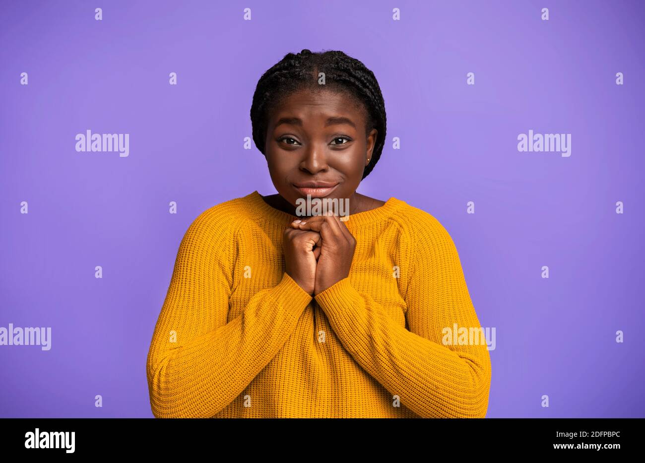 Please, Buy. Cute black woman pleading for something with clasped hands Stock Photo