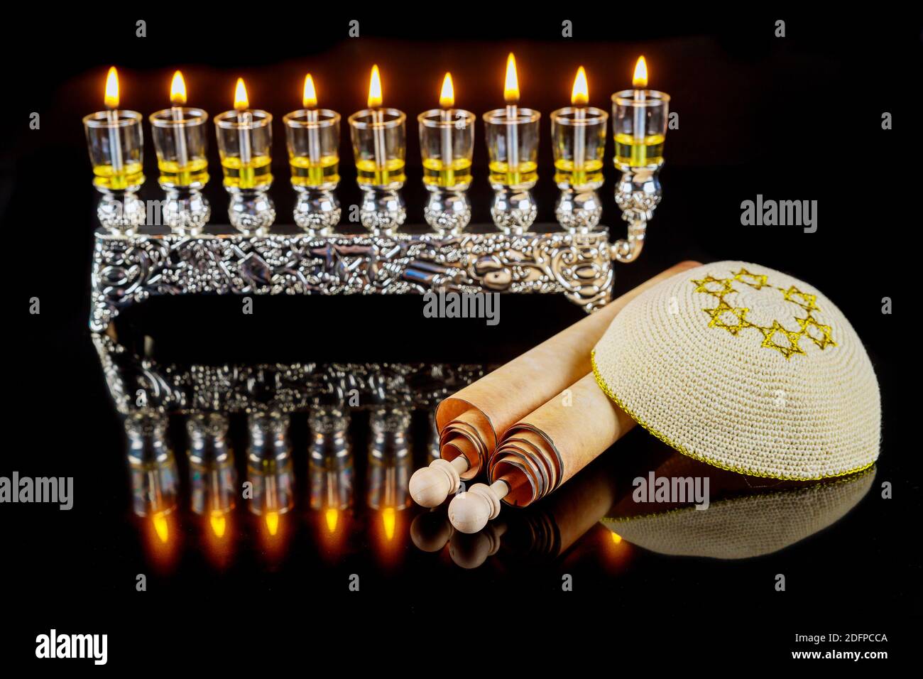 Kippah and totah for Hanukkah on menorah with burning oil candles
