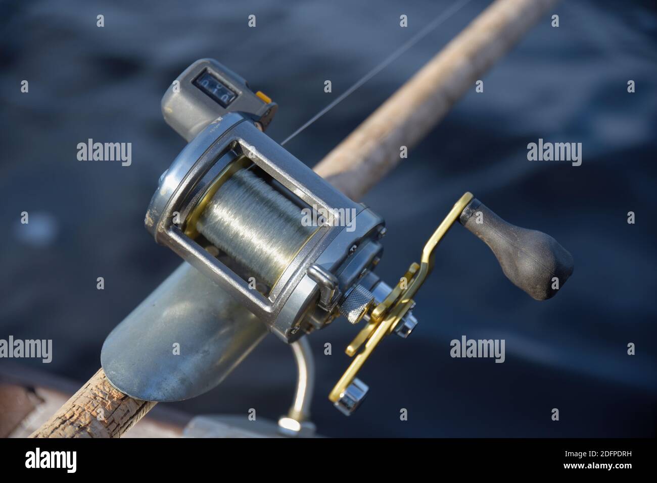 https://c8.alamy.com/comp/2DFPDRH/round-silver-fishing-reel-with-a-line-counter-indicating-almost-10-meters-fishing-line-out-place-in-a-rod-holder-with-blurred-river-water-background-2DFPDRH.jpg