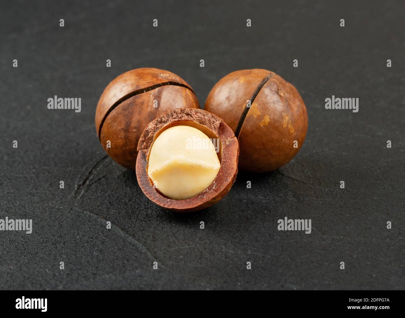 Three macadamia nuts on a dark concrete background Stock Photo