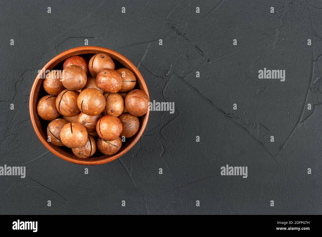Macadamia nuts in a bowl on an empty concrete background Stock Photo