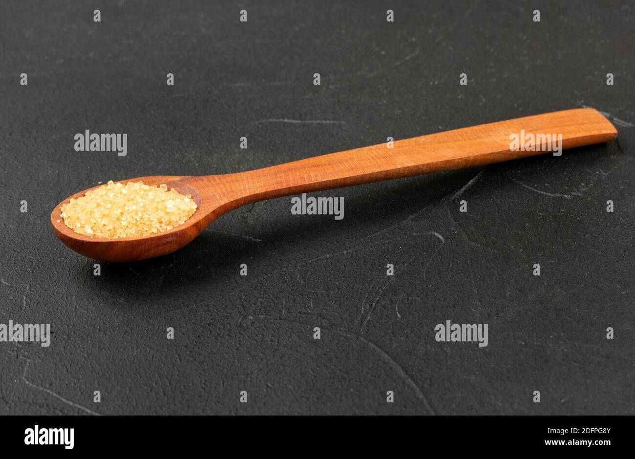 Wooden spoon with brown sugar on a dark background Stock Photo