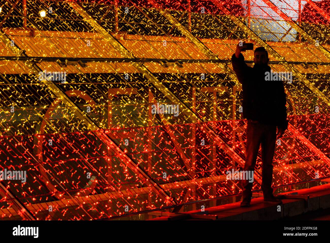 People taking photos with the Christmas lights in the City of Madrid. One of the illuminations where people take photos is next to the Spanish flag in Plaza de Colón, Madrid.Restriction measures for access to Plaza de la Puerta del Sol in Madrid. The Madrid government has made the decision to monitor access to the busy Puerta del Sol square in Madrid after the covid-19 health crisis. Stock Photo
