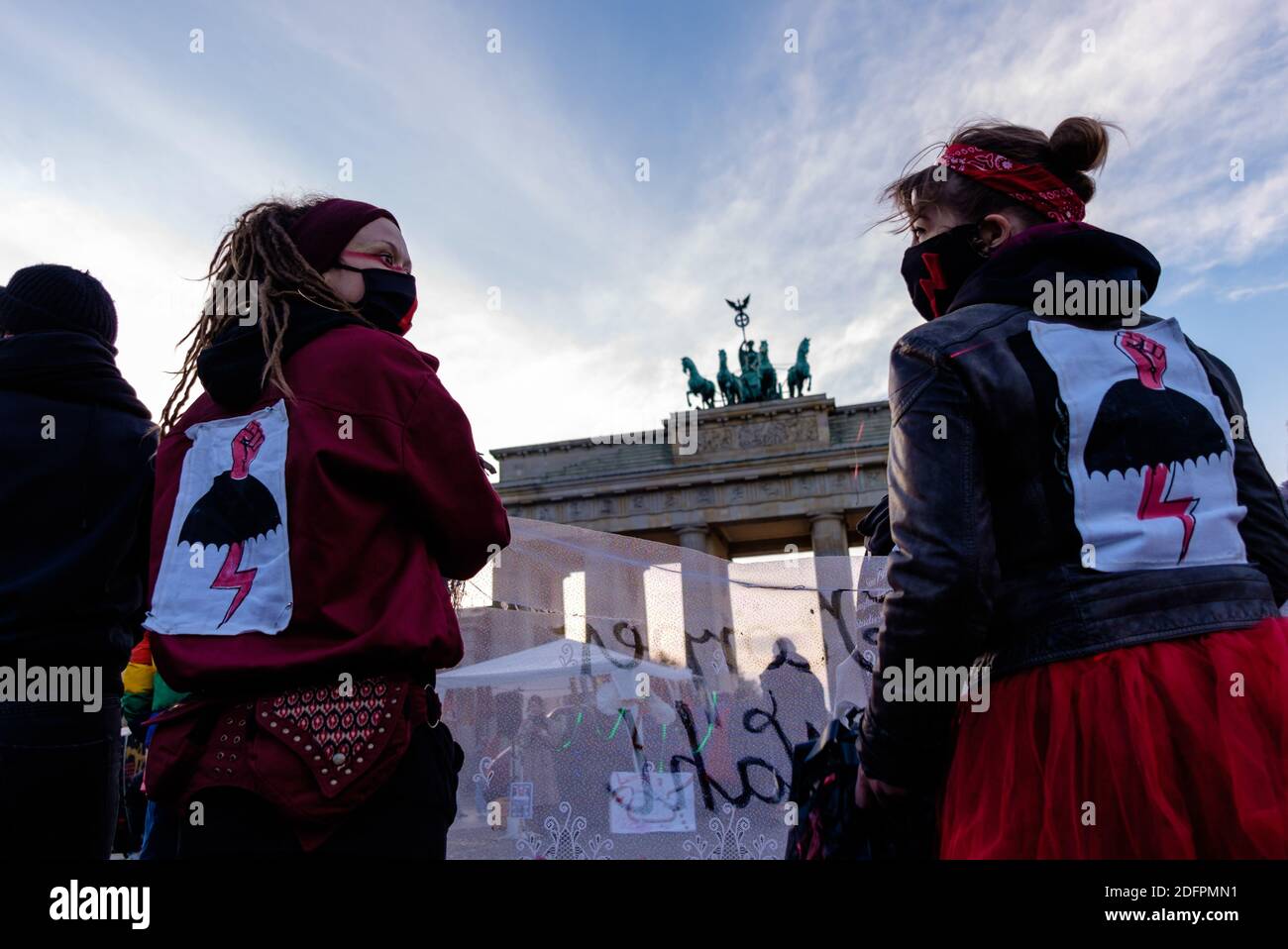 Germany, Berlin, December 06, 2020: Two activists wear a patch of a red lightning bolt, symbol of the Strajk Kobiet in Poland, as queer feminist activist groups rally against patriarchal and repressive behavior at the Pariser Platz in front of the Brandenburg Gate. The organizers want to draw attention to the increased sexism and domestic violence during quarantine as a consequence of the worldwide Covid-19 pandemic and criticize the current legal situation regarding abortion in both Poland and Germany. Poland's constitutional court, controlled by the national populist ruling party PiS, has de Stock Photo