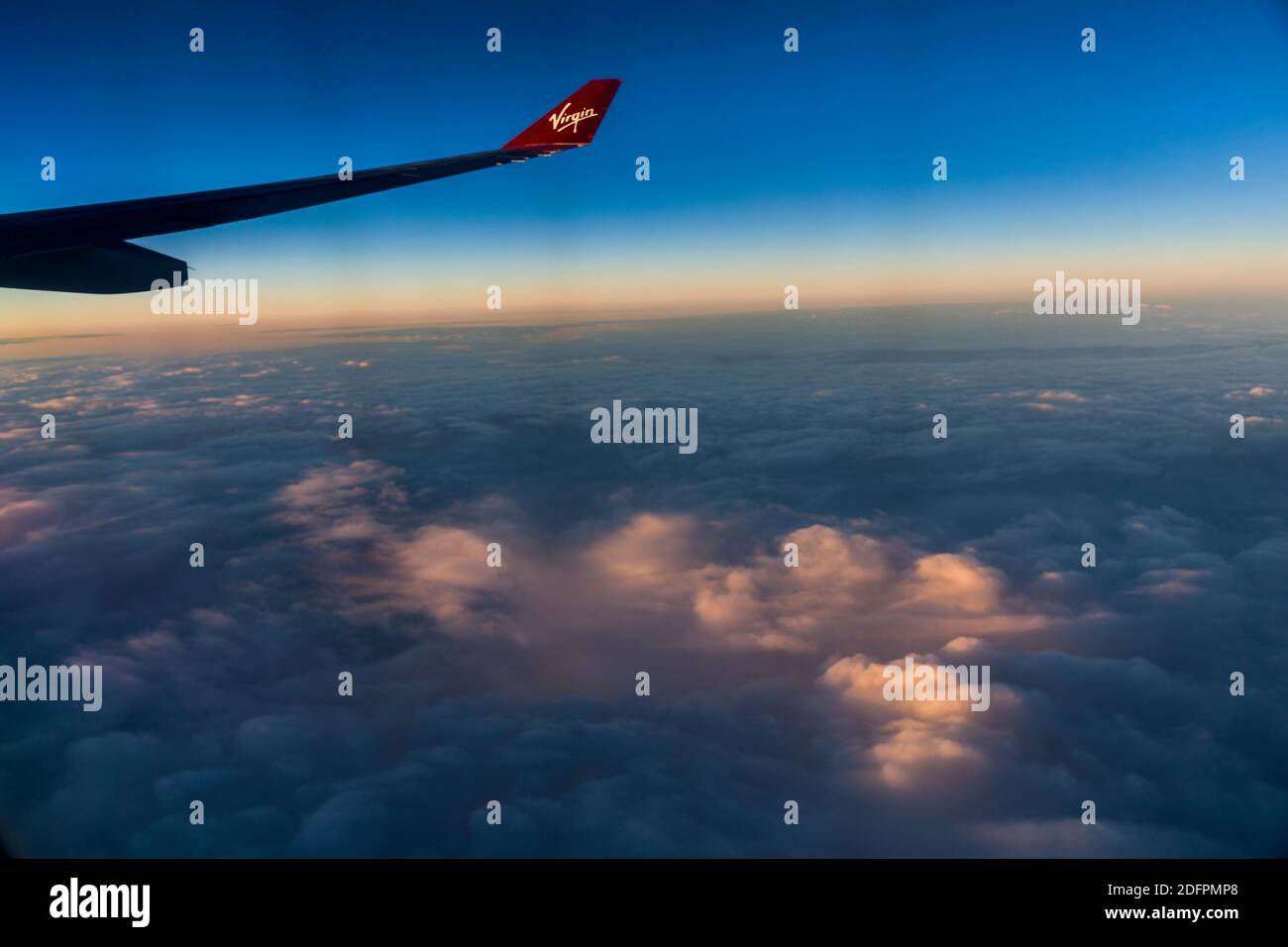 Virgin Atlantic wing tiip in flight over sunrise clouds Stock Photo