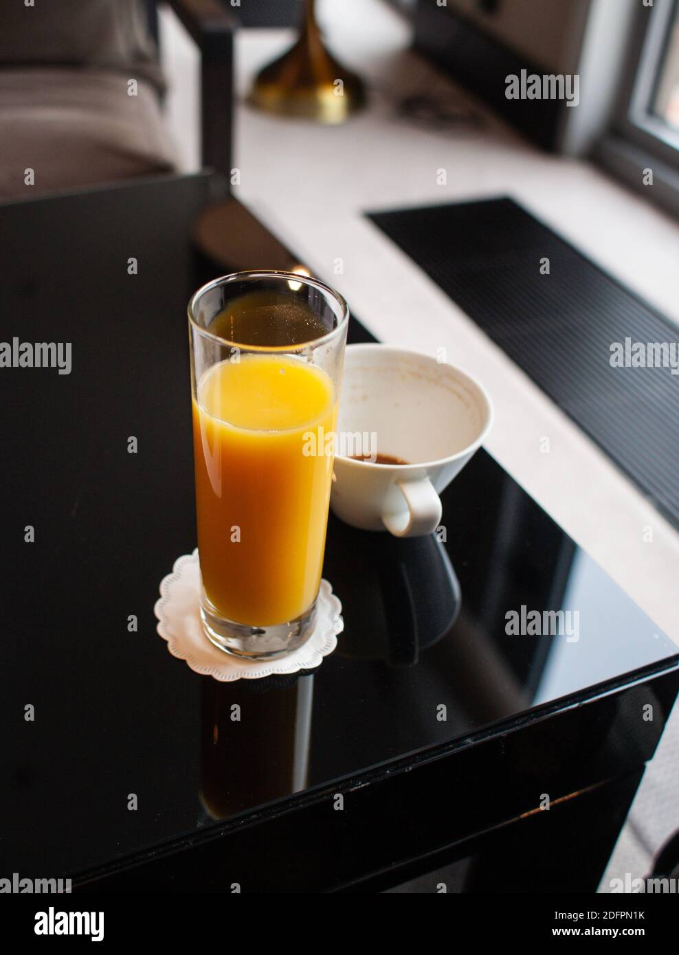 Shallow depth of field (selective focus) image with a glass of orange juice near an almost empty cup of coffee on a table. Stock Photo