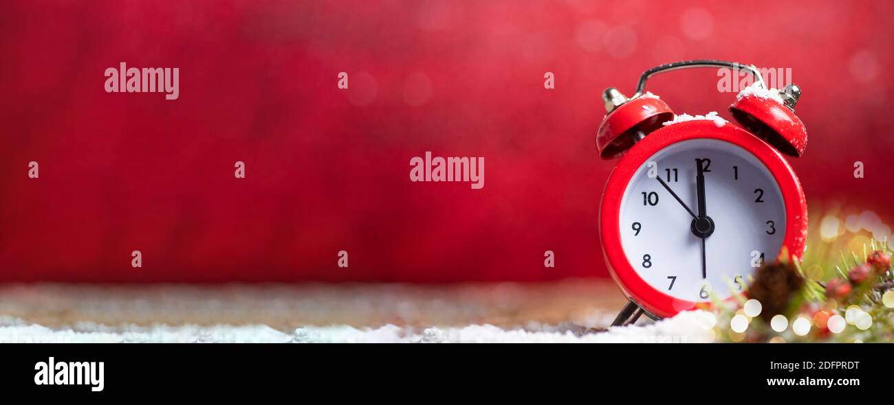 Vintage clock approaching midnight against red Christmas background with large copy space. New Year holidays banner with large space for text Stock Photo