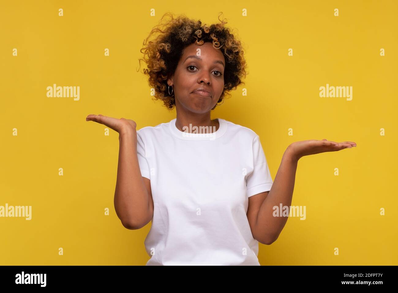 Hesitant African American woman has puzzled expression, shruggs ...