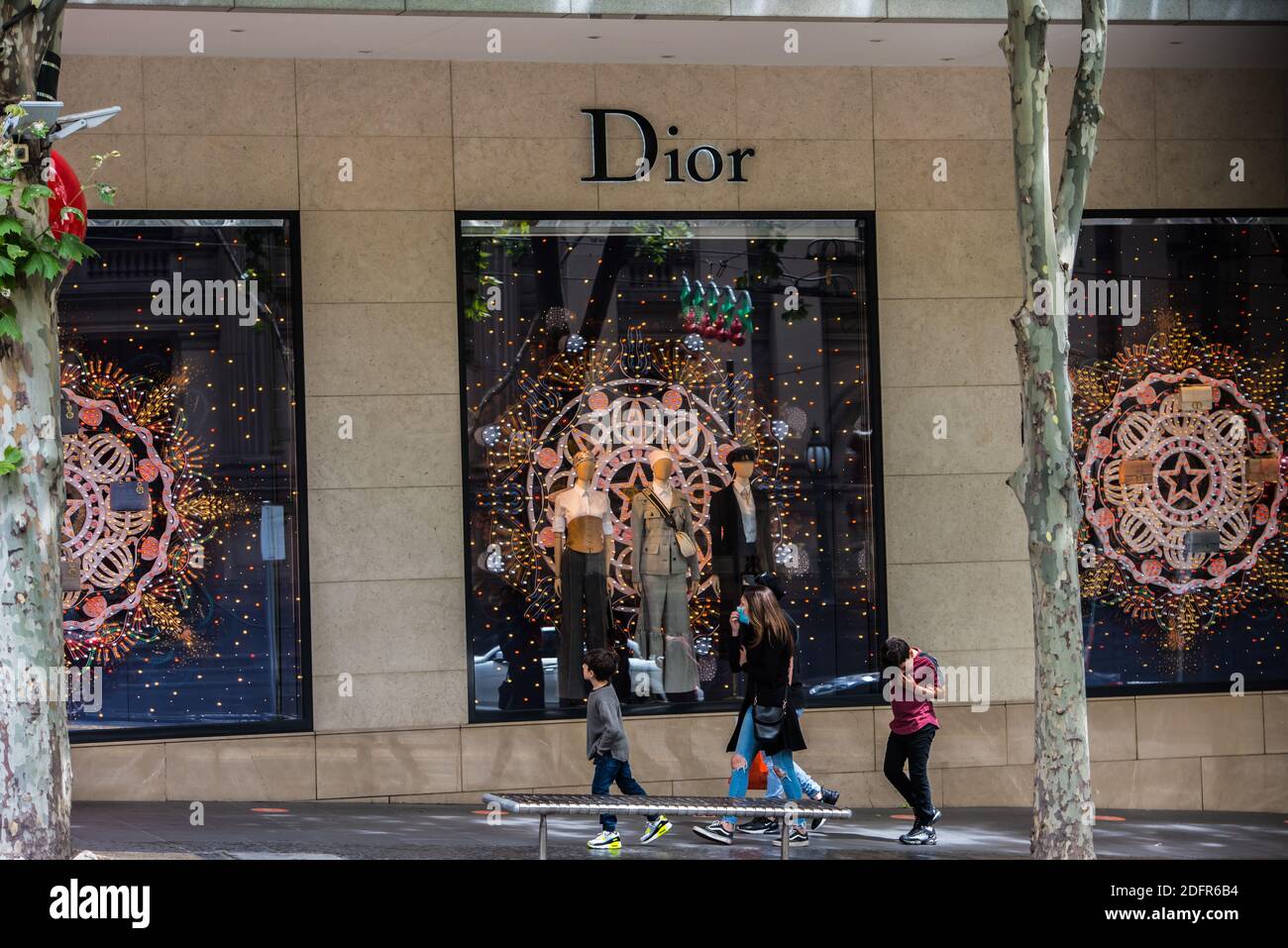 A woman and her kids walk past window displays of Dior store on Collins street Stock Photo Alamy