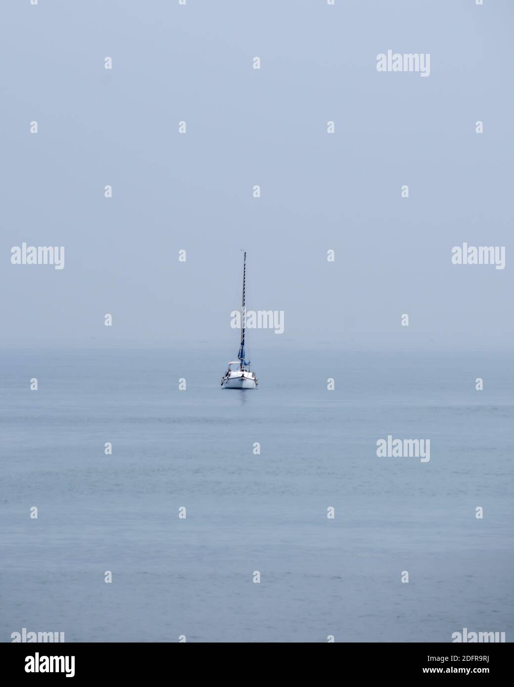 Sailboat in the ocean on cloudy day, no horizon, isolated, no contrast Stock Photo