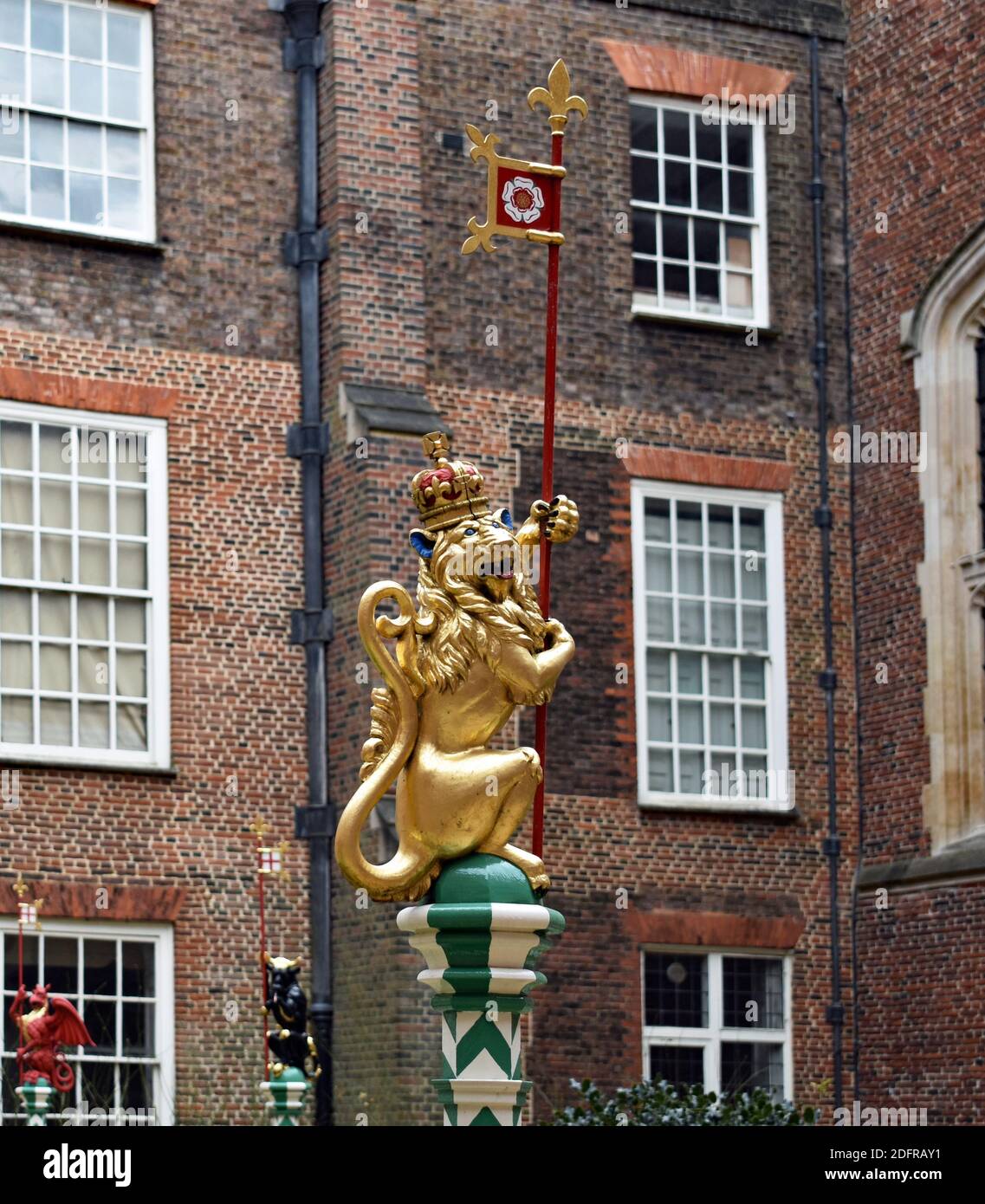 The Chapel Court garden at Hampton Court Palace, London. A golden beast carved in English Oak to a Tudor design stands atop of a green and white pole Stock Photo