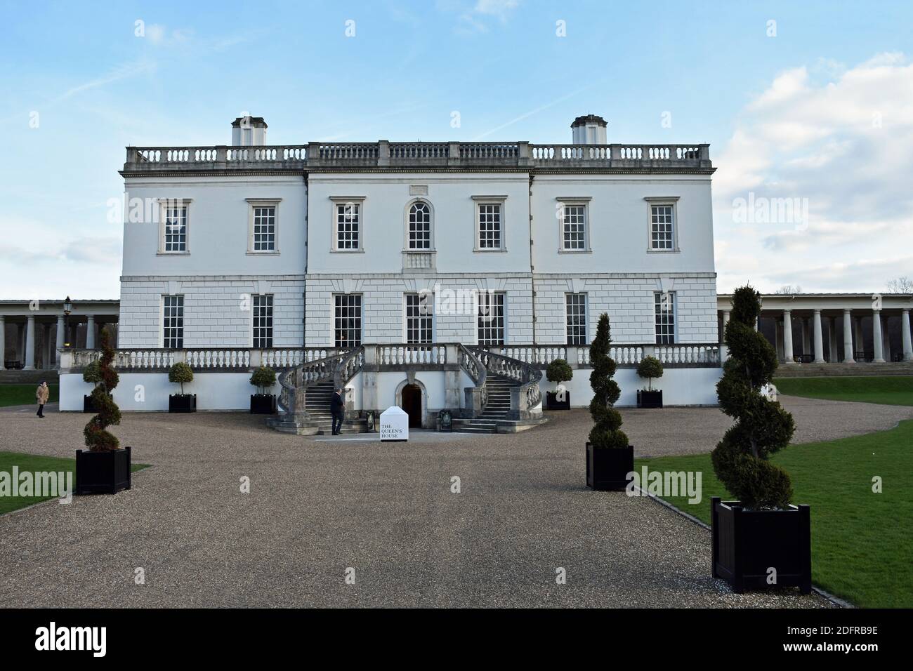 The Queens House, a former royal residence in Greenwich Park, London.   Two staircases lead the way to a raised terrace. A visitor stands outside. Stock Photo