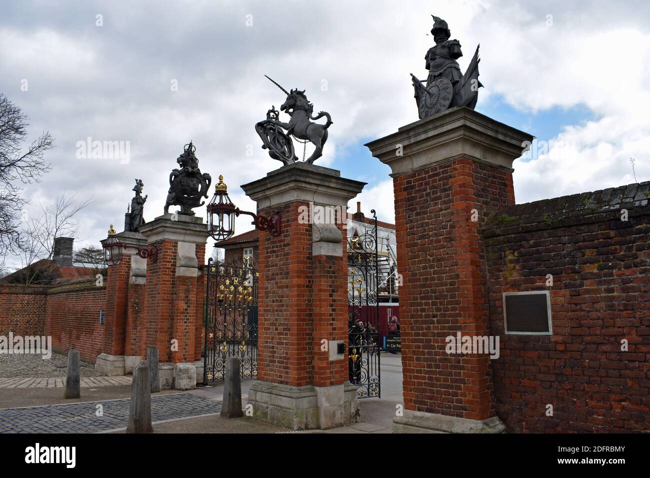 The main entrance gate that leads to the grounds of Hampton Court Palace in Richmond, London. Wall made from red brick and topped with sculptures. Stock Photo
