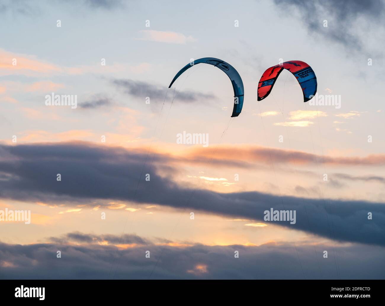Two kites flying high up above clouds in the sky at sunset, Scotland, UK Stock Photo