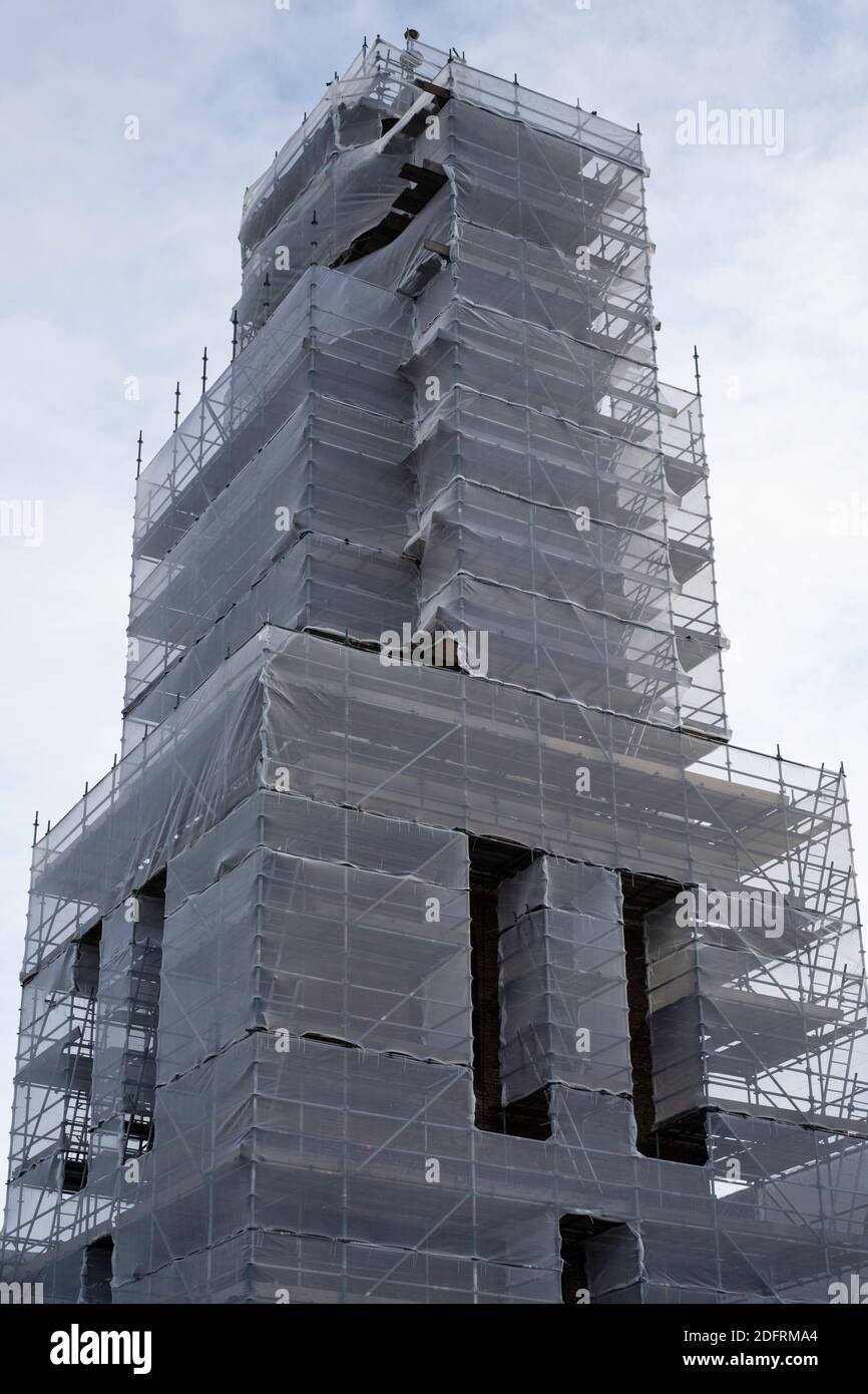 Scaffolding with protective net against Nicolai church tower to prevent building material from falling on the street and people, during renovation Stock Photo