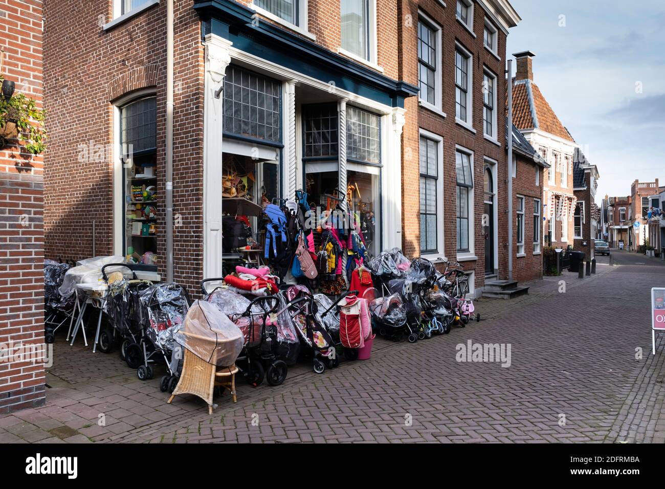 Overcrowded display of bicycles and other items at a sale in front of the entrance and window of a store in Appingedam, Groningen, The Netherlands Stock Photo