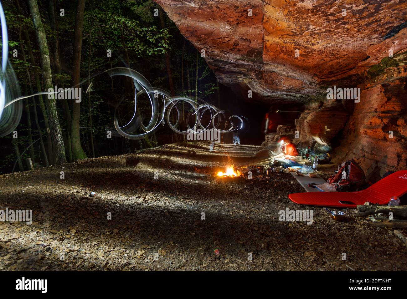 Campfire at campsite under red rocks in palatinate forest at night with light painting Stock Photo