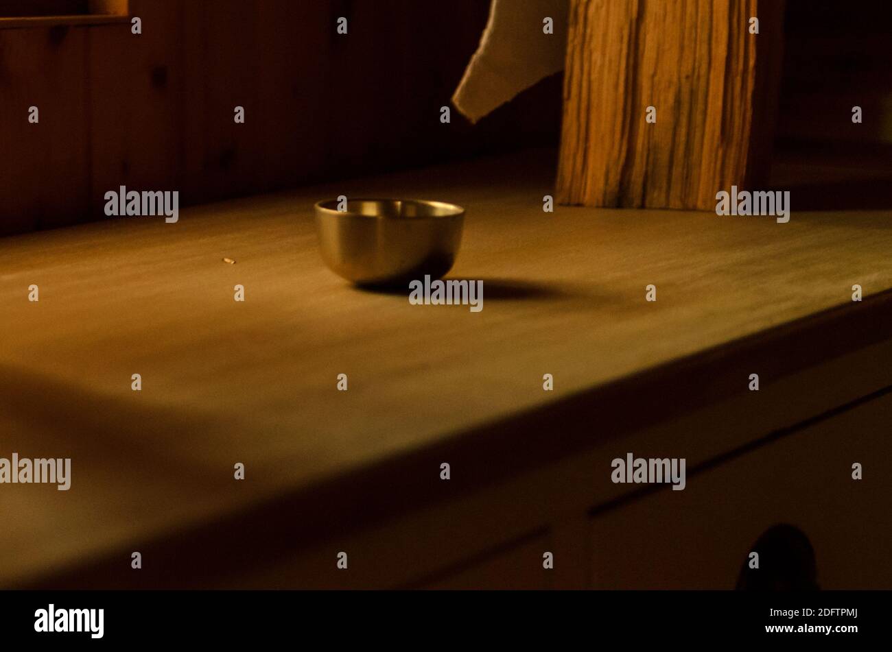 Golden brass singing bowl on a wooden table in dramatic light Stock Photo