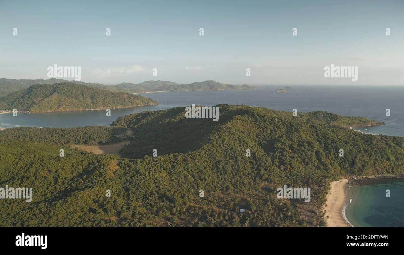 Nobody tropic islands landscapes at sea bay aerial. Green forest on mounts at ocean shore. Palm trees at sand beach. Philippines nature seascape at cinematic drone shot. Visayas Archipelago Stock Photo