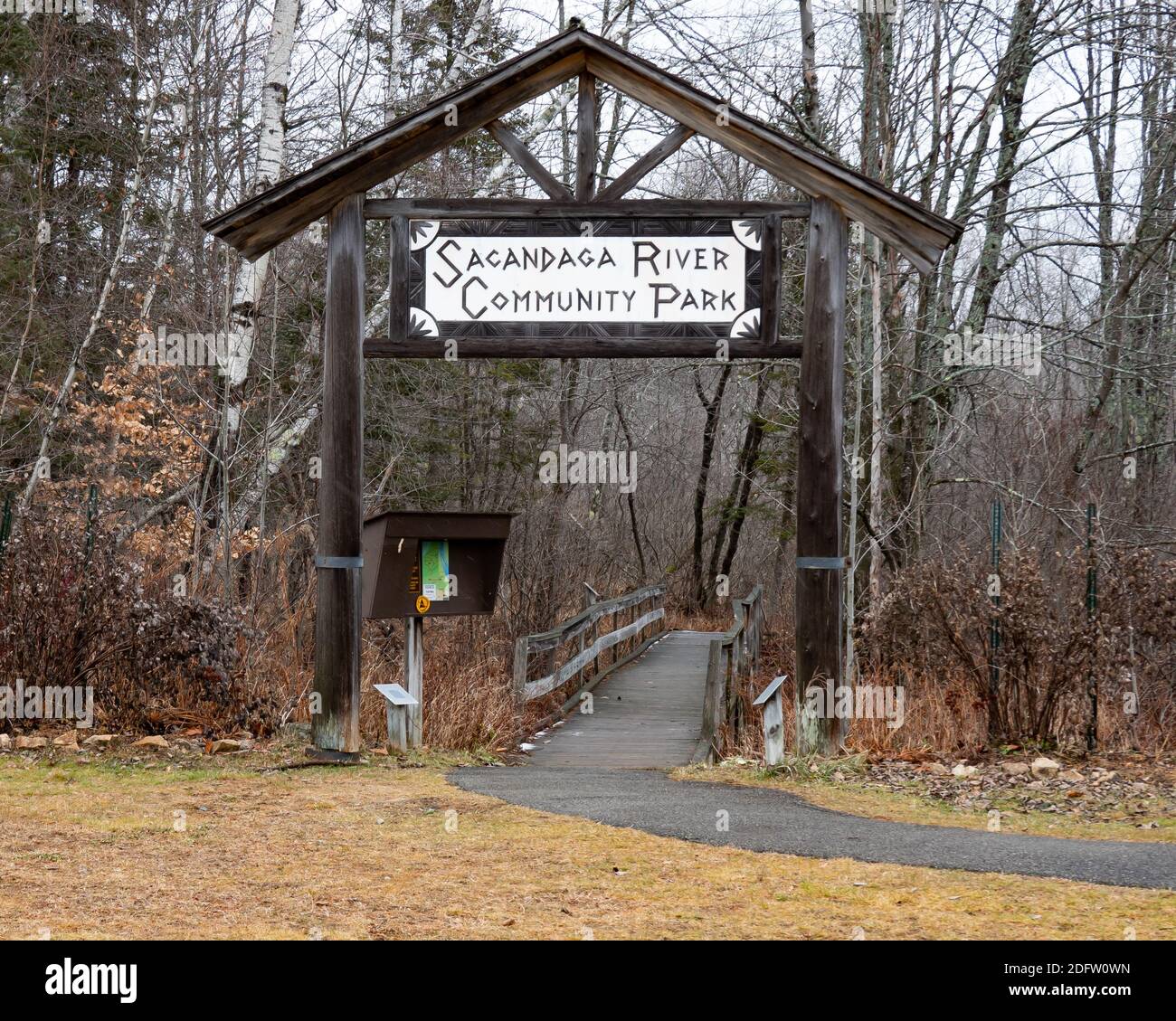Entrance sign to the Sacandaga River Community Park with sign in stand and view of the boardwalk in early winter in the Adirondack Mountains Stock Photo