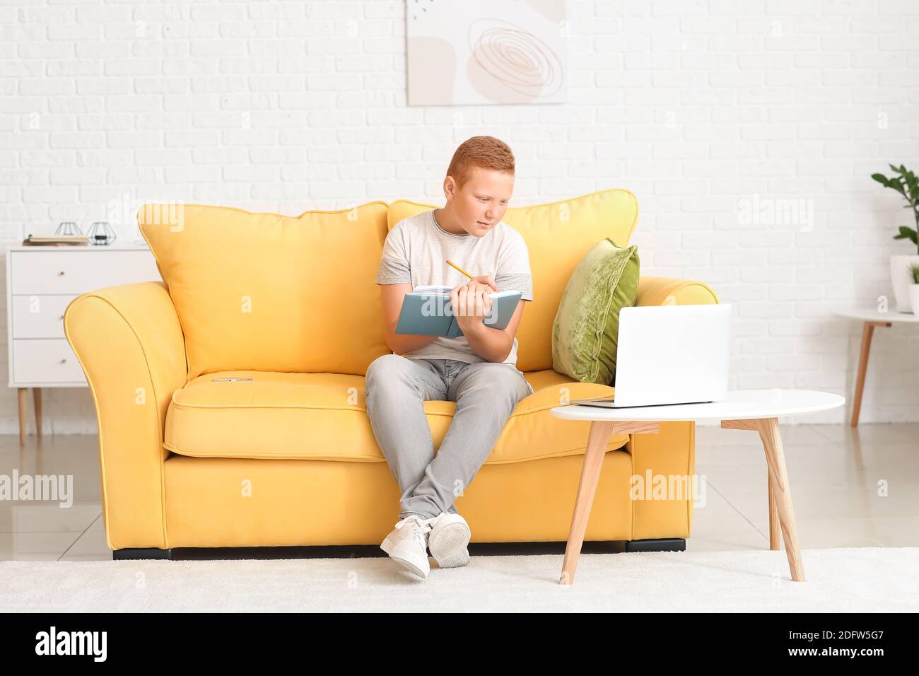 Teenage boy doing homework sitting on sofa at home Stock Photo - Alamy