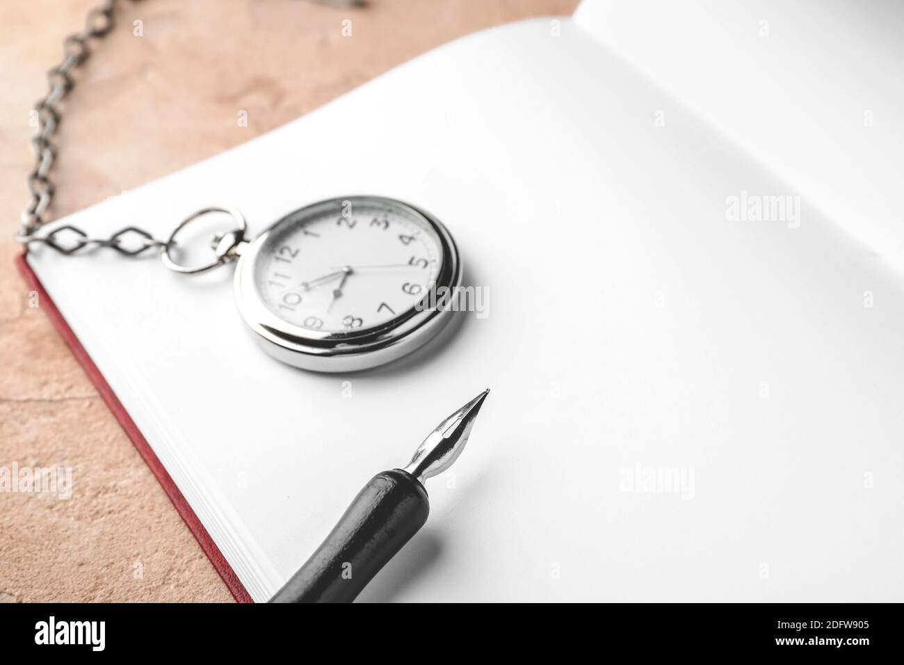 Notebook, pocket clock and nib pen on table Stock Photo