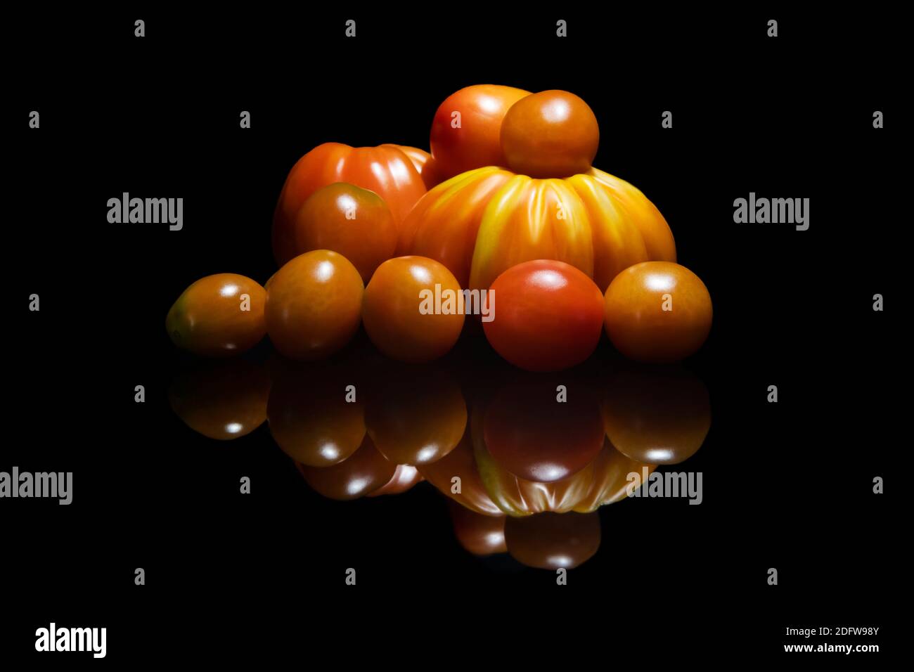 Different kinds of tomatoes piled up under lowlight Stock Photo