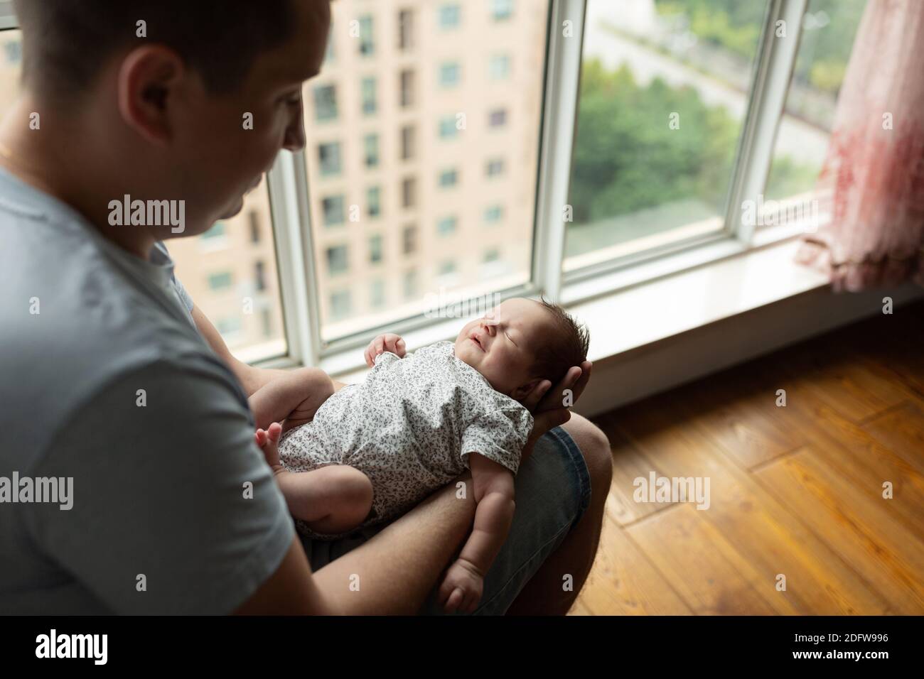 Young Caucasian father holding newborn baby girl. Male man parent and child daughter. Authentic lifestyle documentary moment. Single dad family life Stock Photo