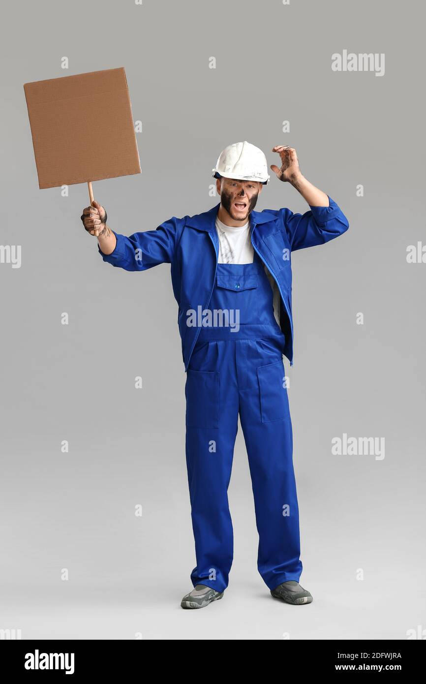 Protesting miner man with placard on grey background Stock Photo