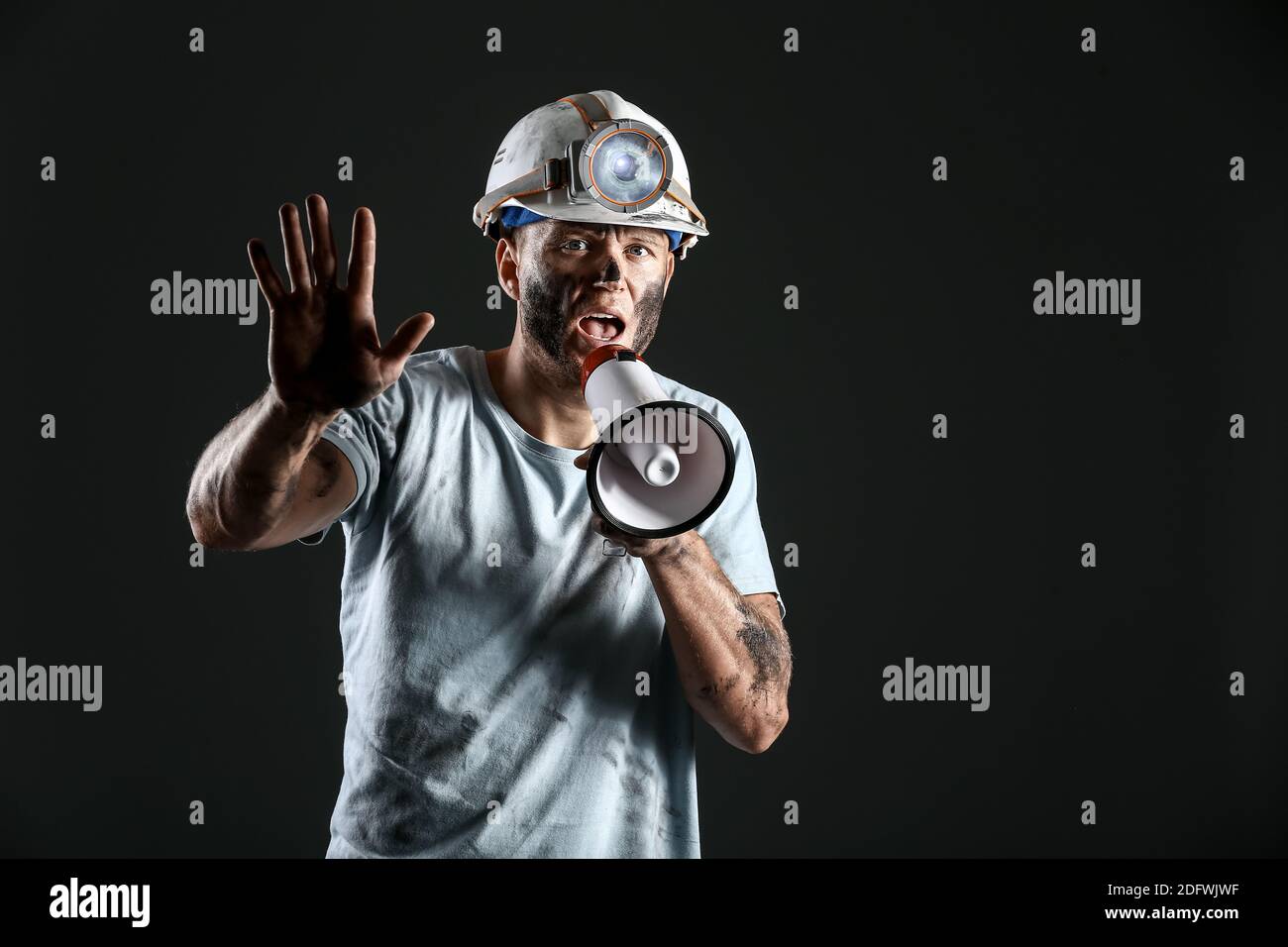 Protesting miner man with megaphone on dark background Stock Photo