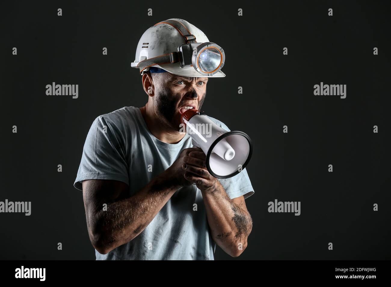 Protesting miner man with megaphone on dark background Stock Photo