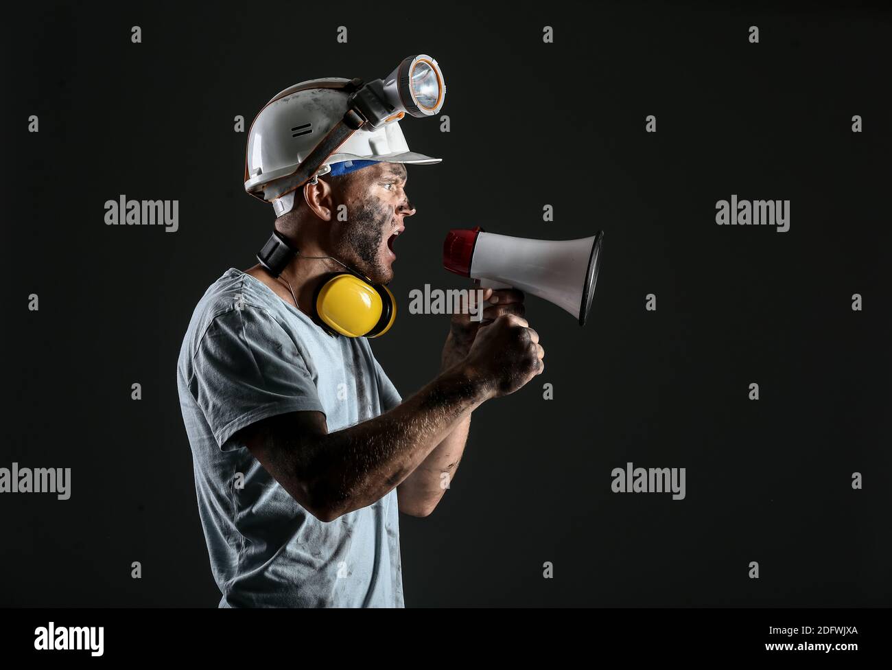 Protesting miner man with megaphone on dark background Stock Photo