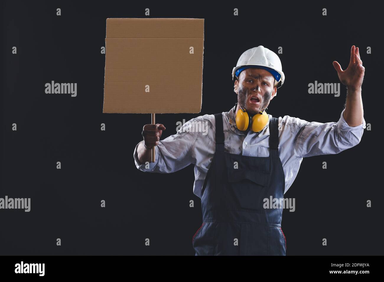 Protesting miner man with placard on dark background Stock Photo