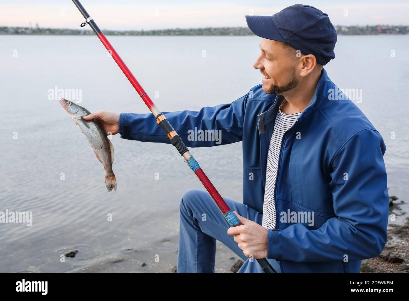 Young Man At Lake Casting Fishing Rod Stock Photo - Download Image