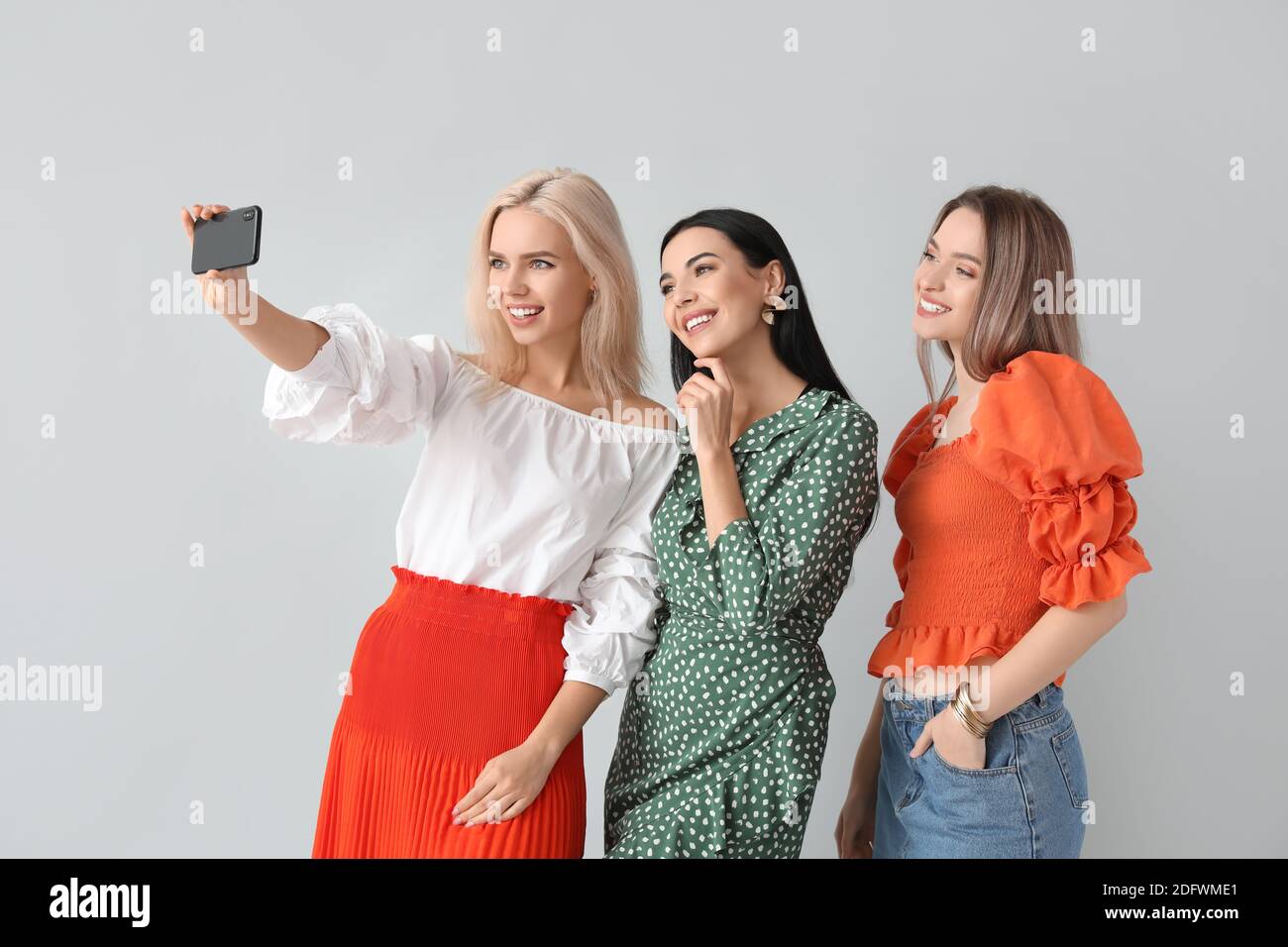 Beautiful young women taking selfie on grey background Stock Photo - Alamy