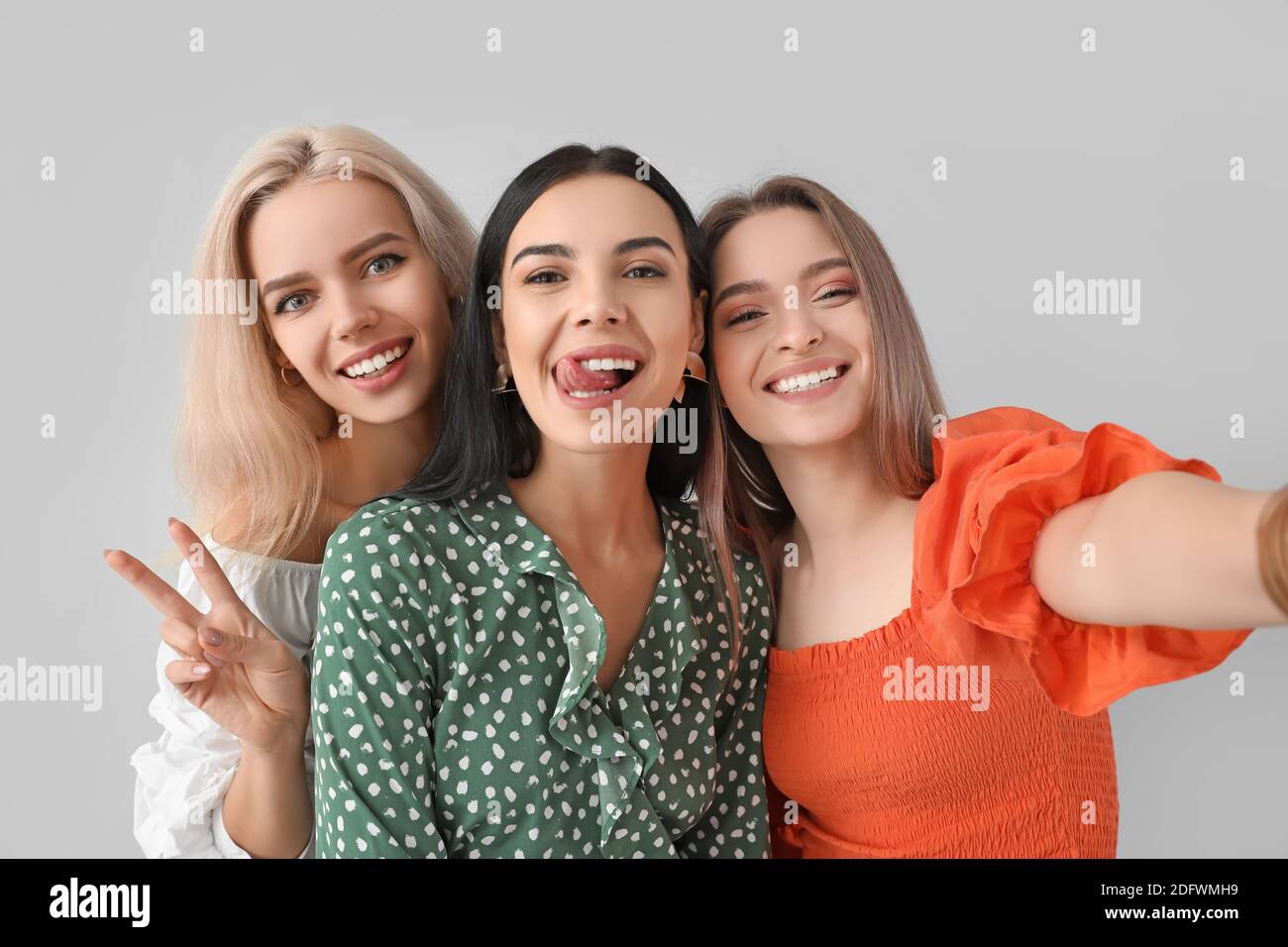 Beautiful young women taking selfie on grey background Stock Photo - Alamy