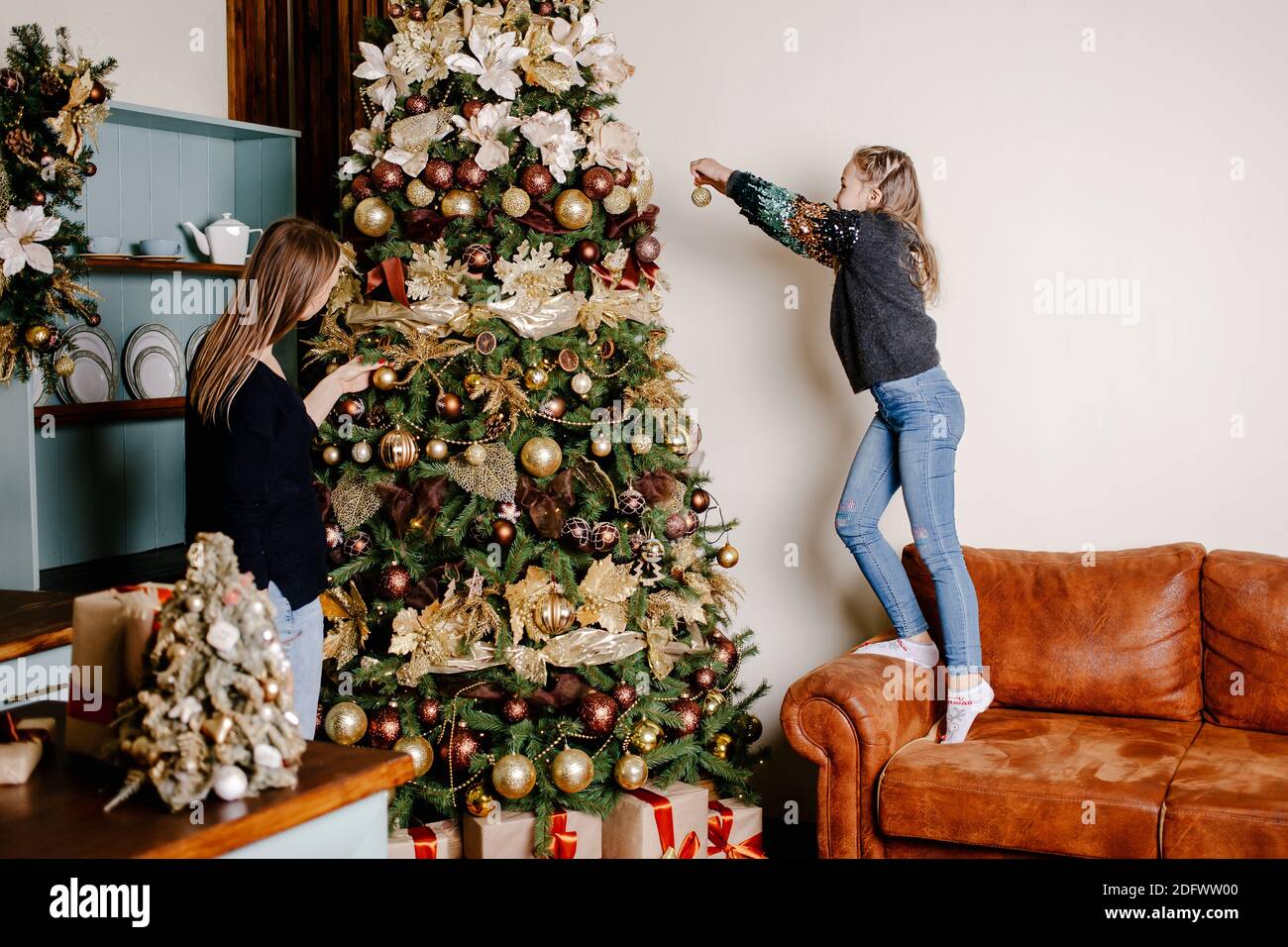 Mom and daughter decorates a Christmas tree in the living room. Christmas, decoration, holidays and people concept. Happy family. Stock Photo