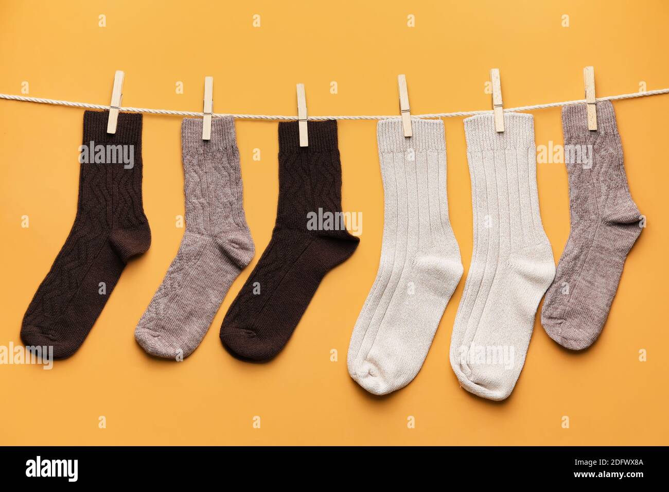 Rope with warm socks on color background Stock Photo - Alamy
