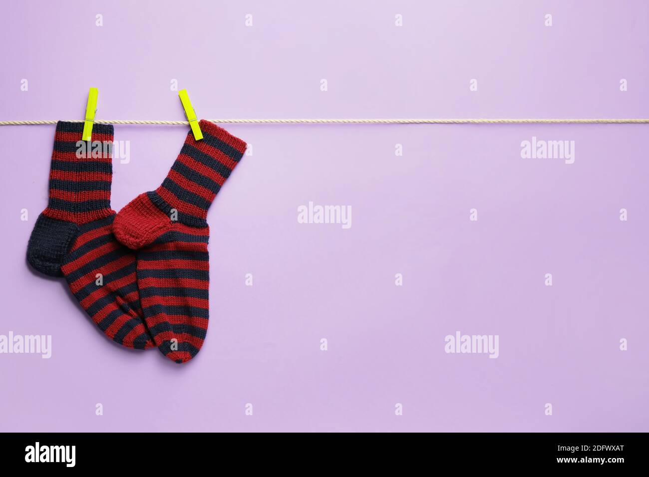 Rope with warm socks on color background Stock Photo - Alamy