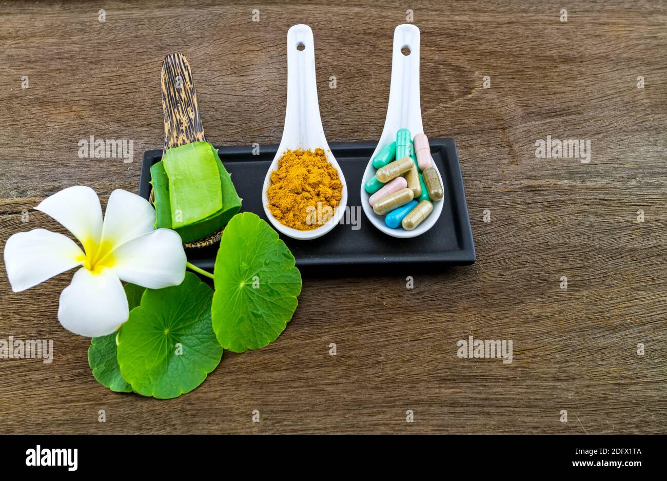 Spa herbal ( white frangipani flowers ,turmeric powder in white spoon ,pill,Aloe vera essential oil and gel,Green Asiatic Pennywort ) on wooden backgr Stock Photo