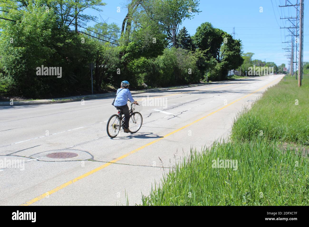 Older woman on a bicycle on Lehigh Avenue in Morton Grove, Illinois Stock Photo