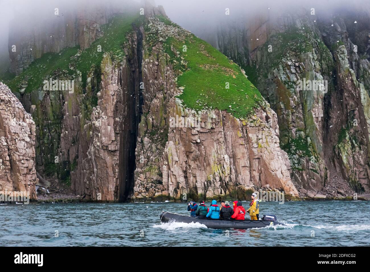 Tourists on zodiac reaching the island, Cape Archen, Bering Sea, Russian Far East Stock Photo