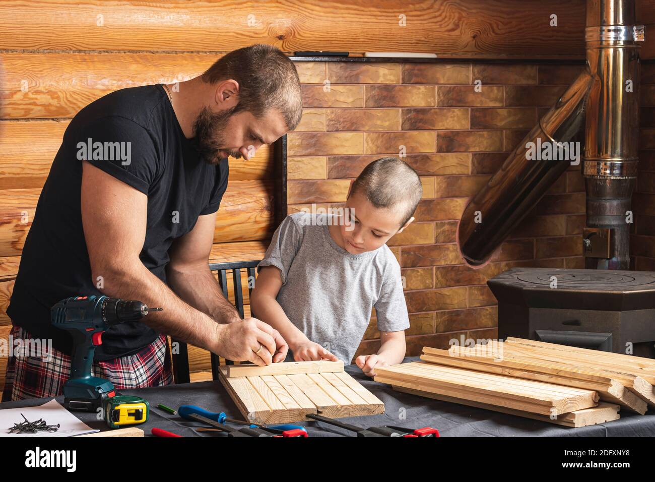 Dad and son are working on a wooden product, making markings for