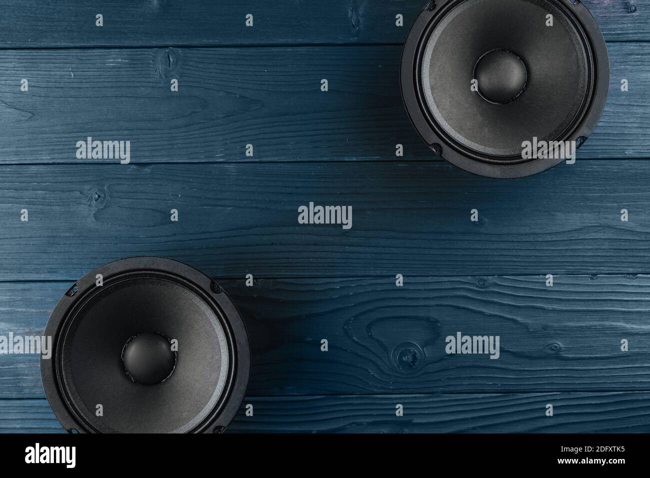 Car audio, black car speakers lie on a blue wooden background. Stock Photo