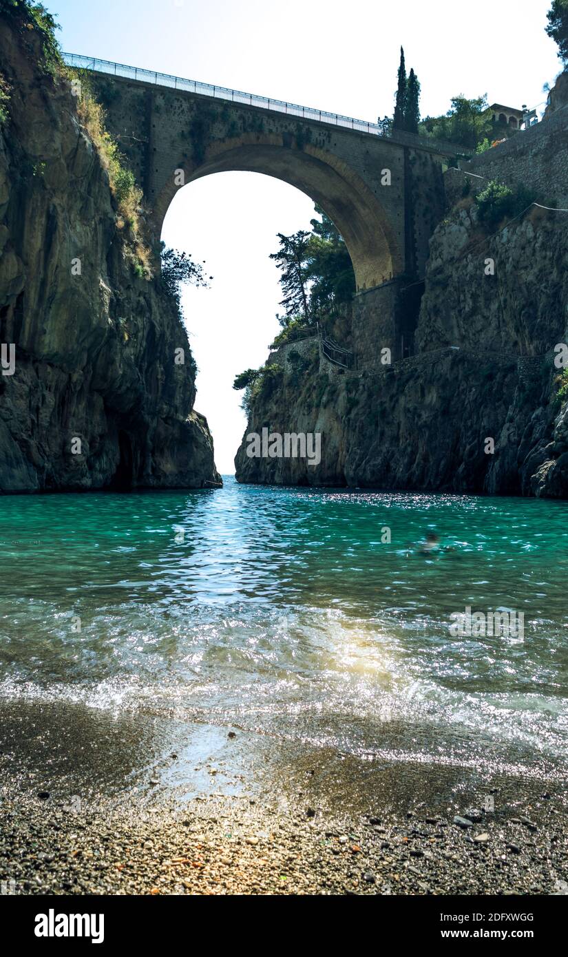 Fiordo di Furore, Amalfi coast, picturesque seascape view from beach on arched bridge between rocks and turquoise sea. Stock Photo